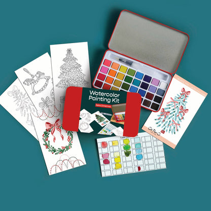 A watercolor painting kit arranged on a teal background, including an open red metal case with multiple paint wells, several printed coloring/illustration cards, a green booklet, and a small palette sheet.