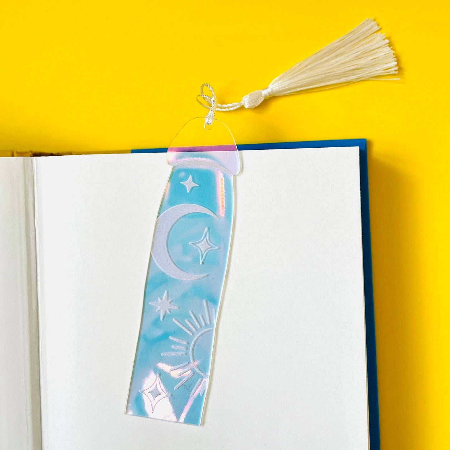 Decorative bookmark with celestial design on an open book against a yellow background