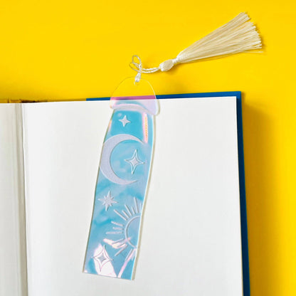 Decorative bookmark with celestial design on an open book against a yellow background