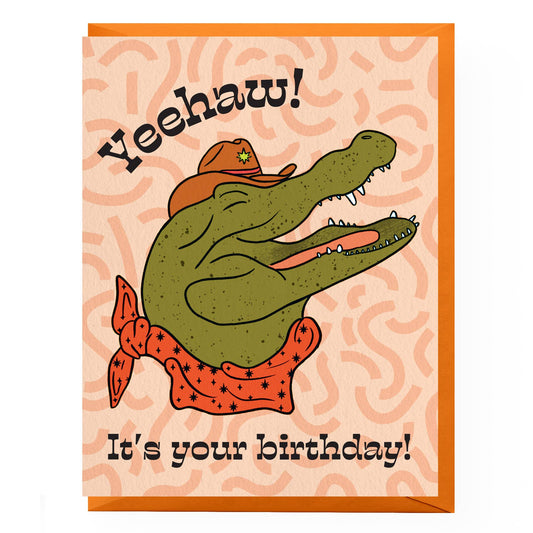 Birthday card with an alligator wearing a cowboy hat and bandana, text 'Yeehaw! It's your birthday!' on a patterned background.