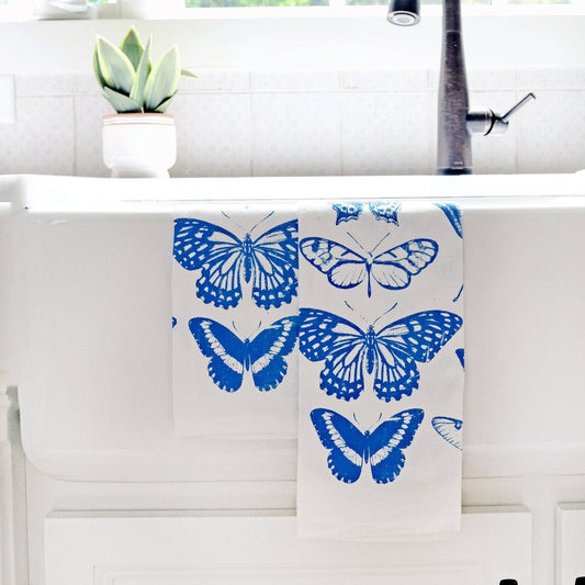 Butterfly patterned towel hanging over a kitchen sink with a window in the background