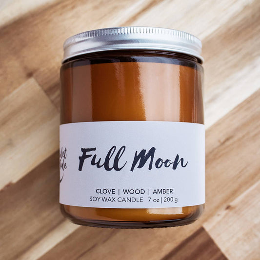 Candle jar labeled 'Full Moon' on a wooden surface