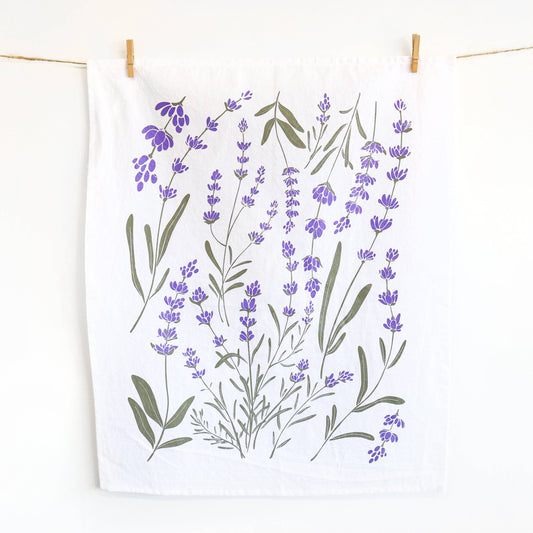 Tea towel with lavender design hanging on a line against a white background