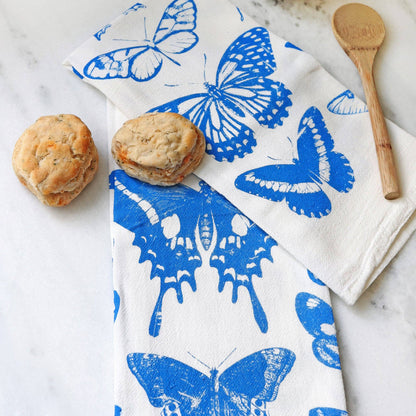 Butterfly-patterned towel on a marble surface with biscuits and a wooden spoon.