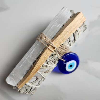 Decorative item with crystal, wooden stick, and blue evil eye charm on a light gray background