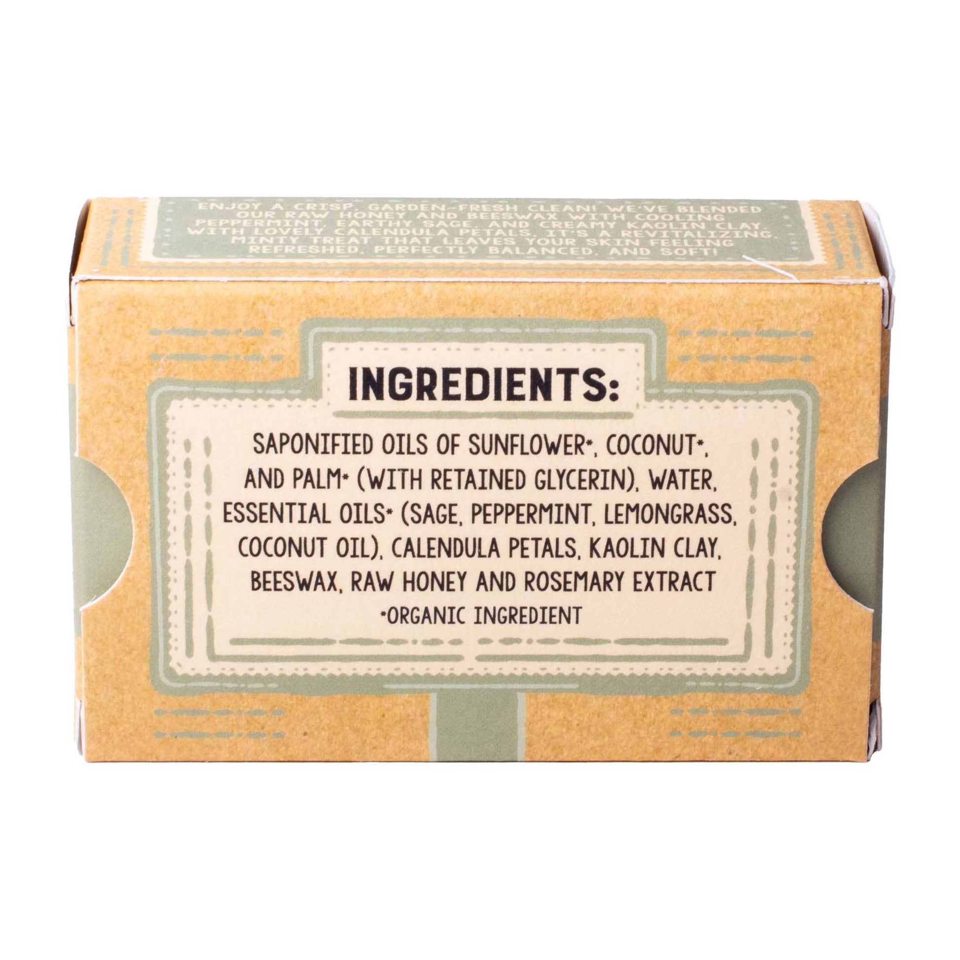 A square kraft paper box with a large white label detailing the ingredients, including saponified oils of sunflower, coconut, and palm, water, and essential oils like sage, peppermint, and lemongrass. The box is photographed on a clean white background.
