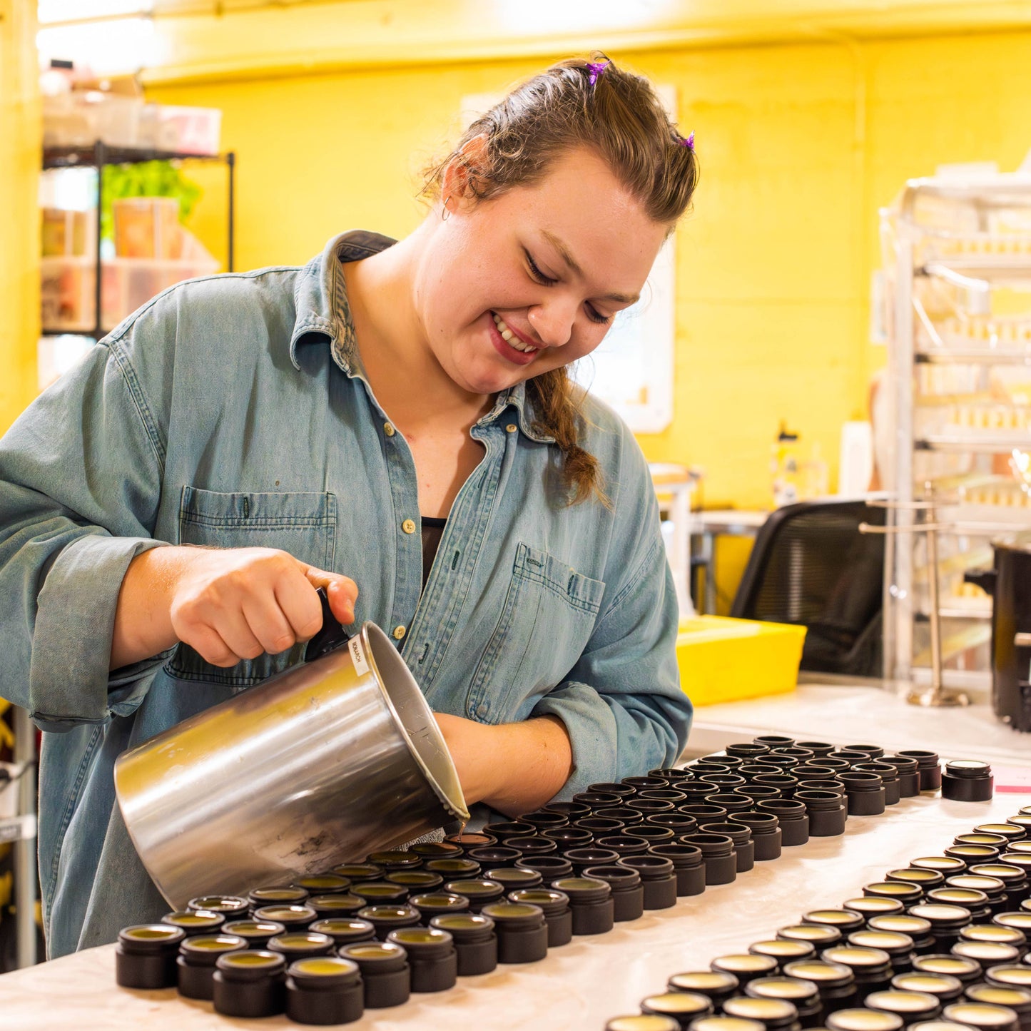 Person working with containers on a table in a yellow-walled room