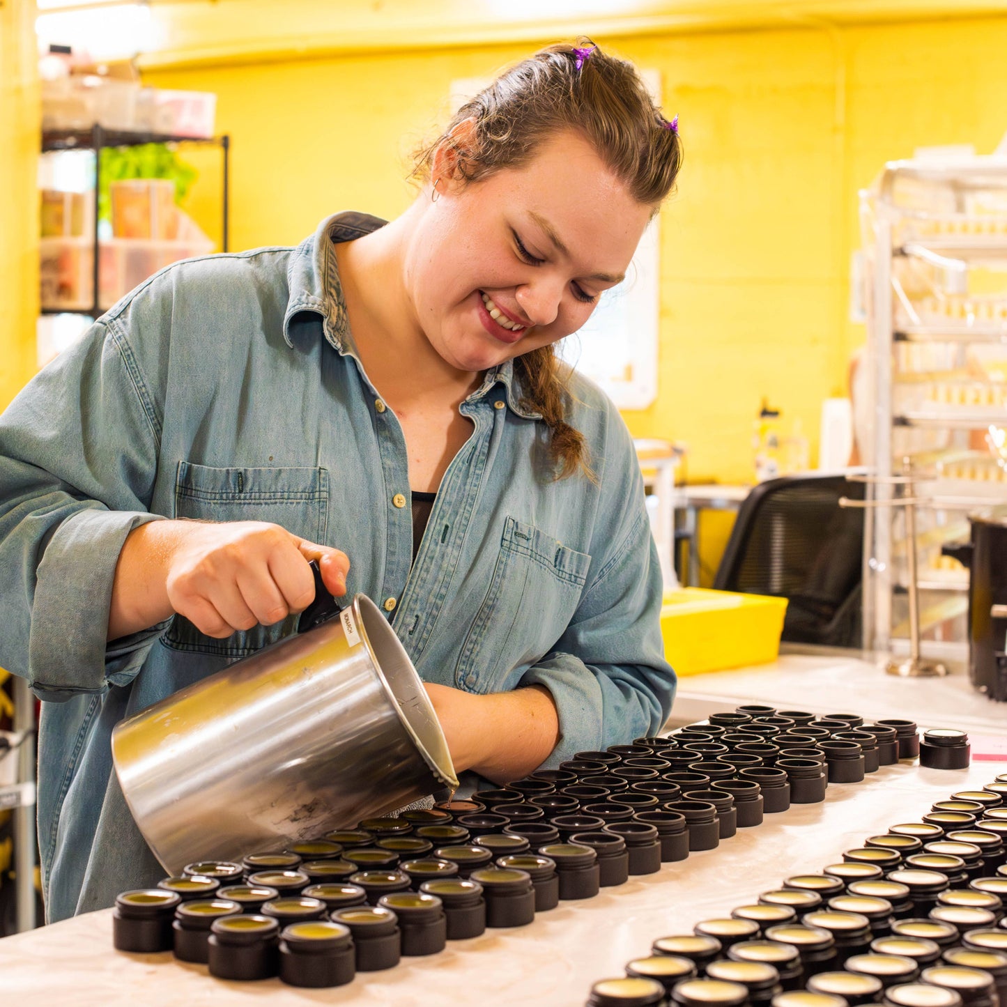 Person working with containers on a table in a yellow-walled room
