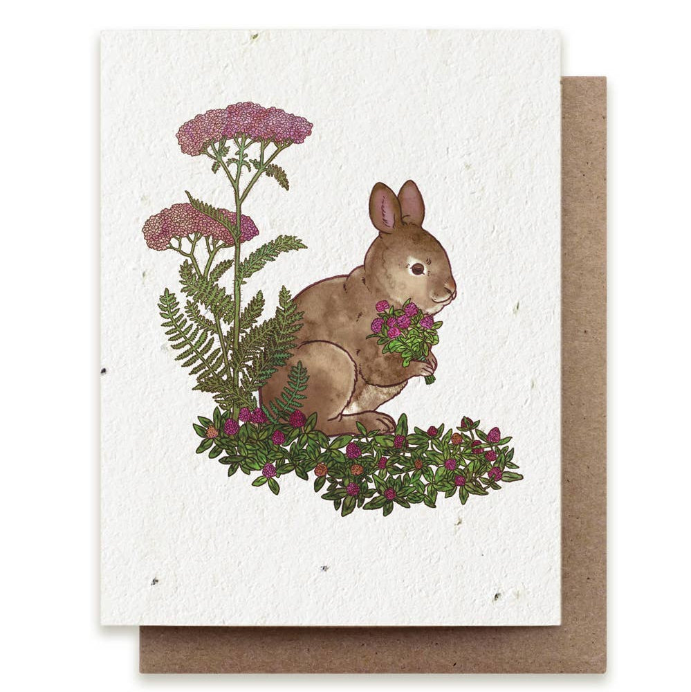 Greeting card with a rabbit illustration surrounded by flowers and plants on a white background.