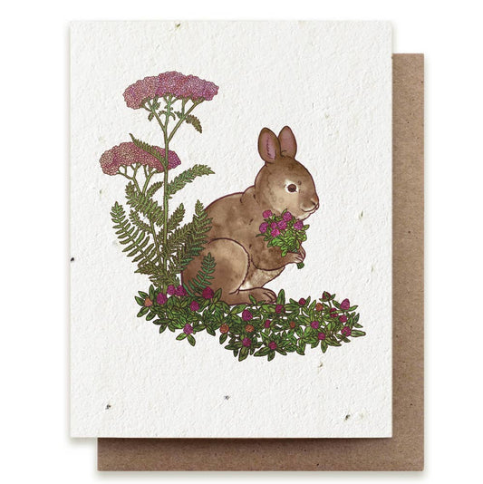 Greeting card with a rabbit illustration surrounded by flowers and plants on a white background.