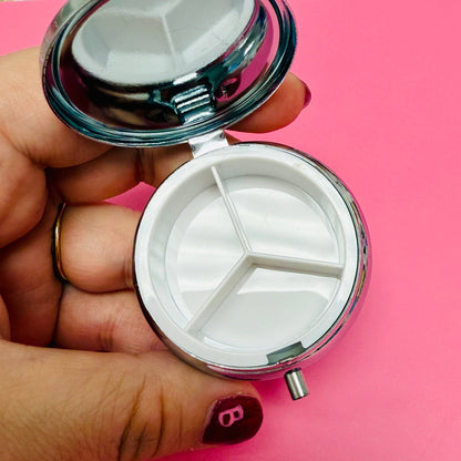 Hand holding a small round mirror with a pink background