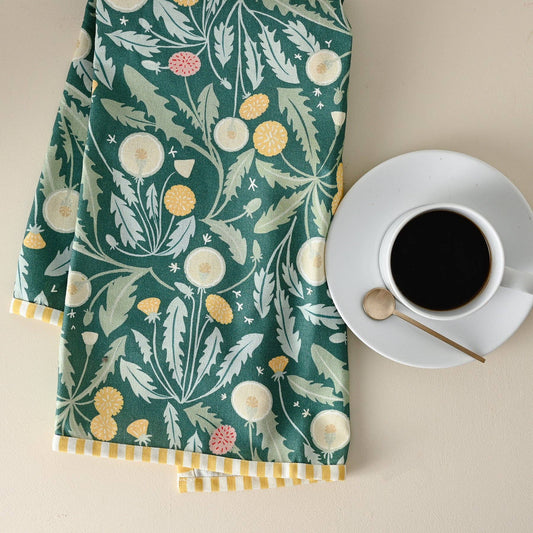 Tea towel with floral pattern next to a cup of coffee on a beige surface