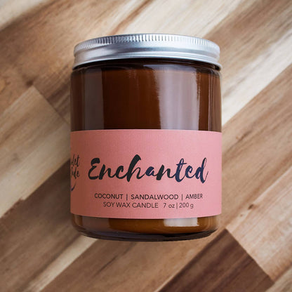 Candle jar with 'Enchanted' label on a wooden surface