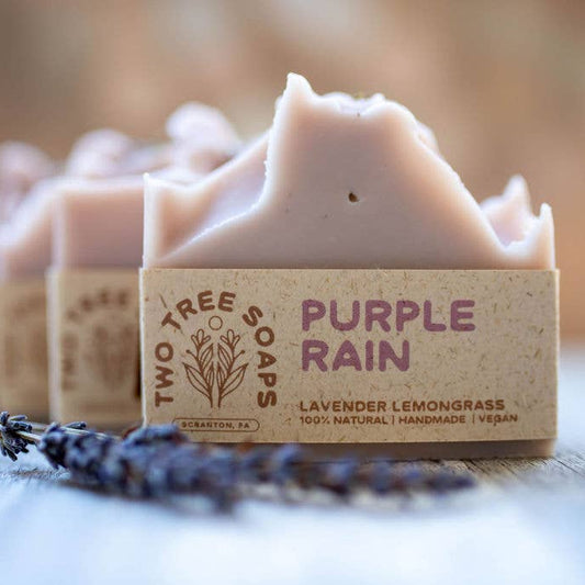 Bar of soap with 'Purple Rain' label on a wooden surface with blurred background