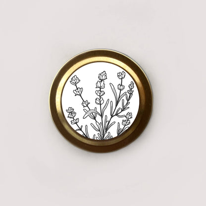 Round brass object with black floral design on a white background