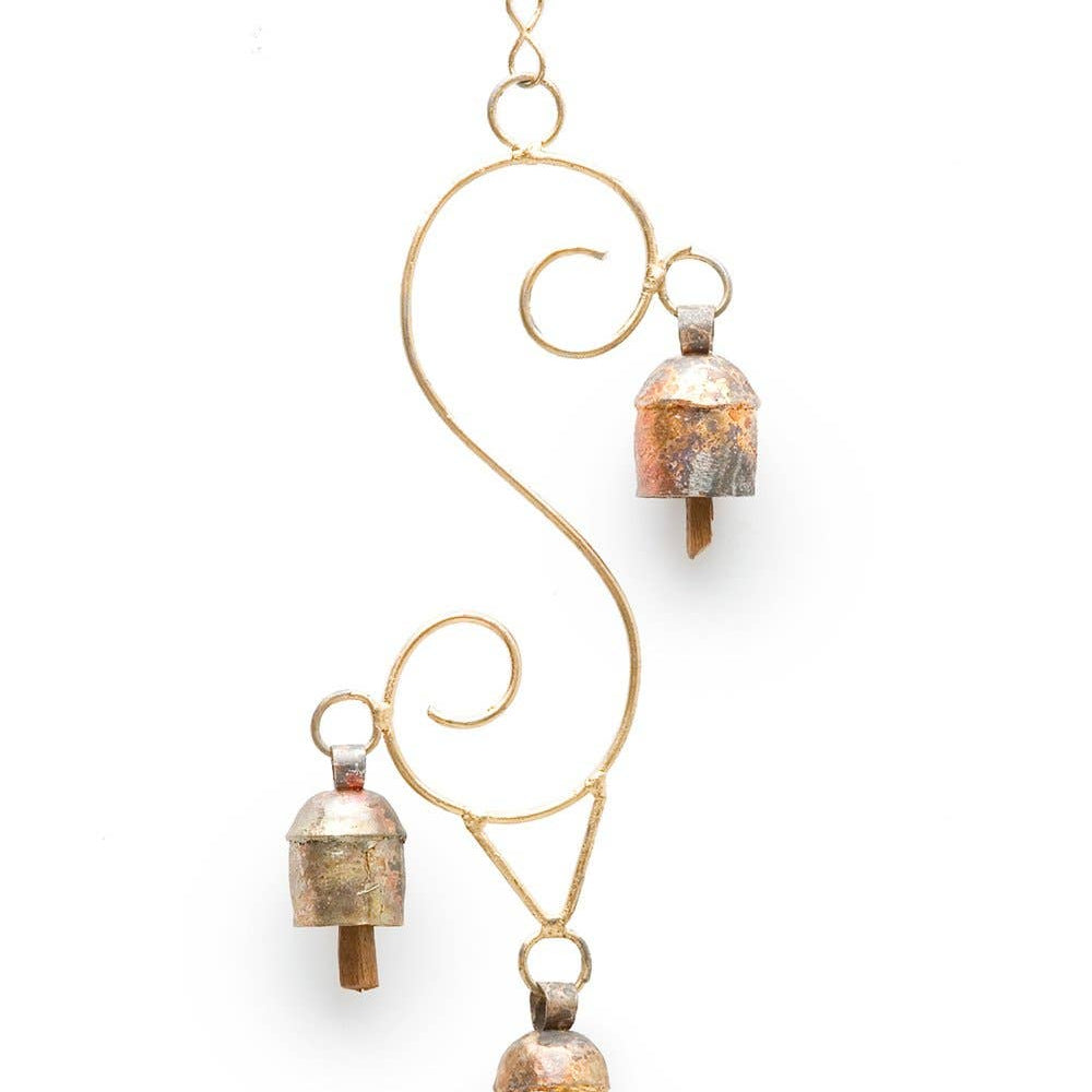 A decorative hanging wall ornament featuring a gold-toned metal scrollwork frame with three small bell-shaped hanging elements, each showing a textured copper and gold finish, set against a plain white background.