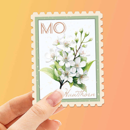Hand holding a decorative card with a floral design and 'MO' initials on an orange background