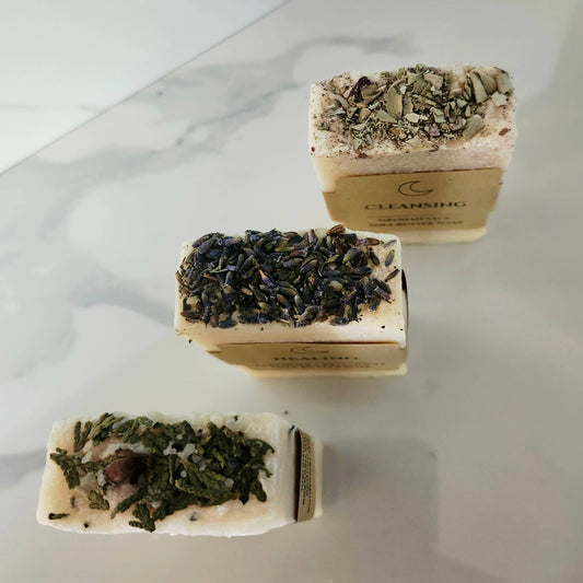 Three rectangular soap bars with green herb mixture on a marble surface