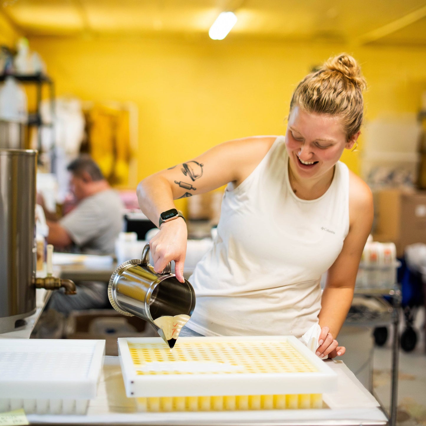 Person in a kitchen pouring liquid into containers on a counter.