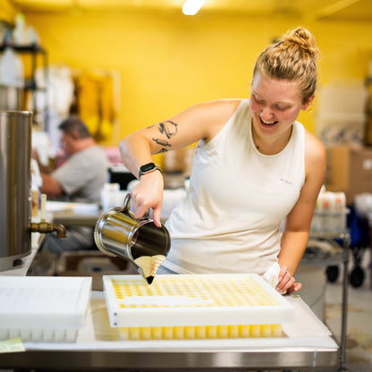 Person in a kitchen pouring liquid into containers on a counter.