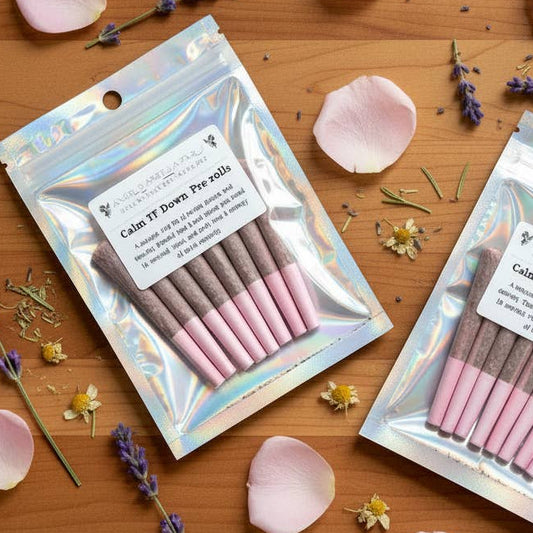 Two packages of pink and brown makeup brushes on a wooden surface with rose petals and lavender flowers.