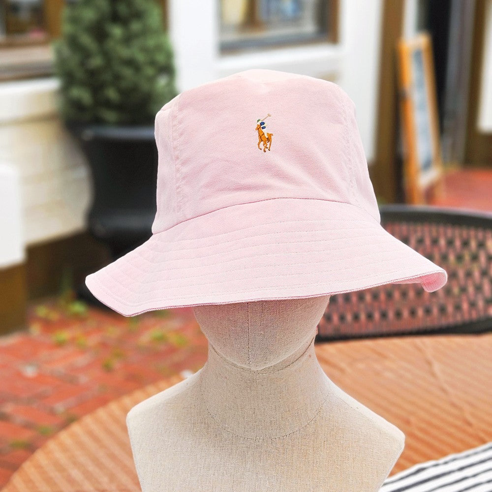 Pink Bucket Hat on a manneqin head on an outdoor table. 