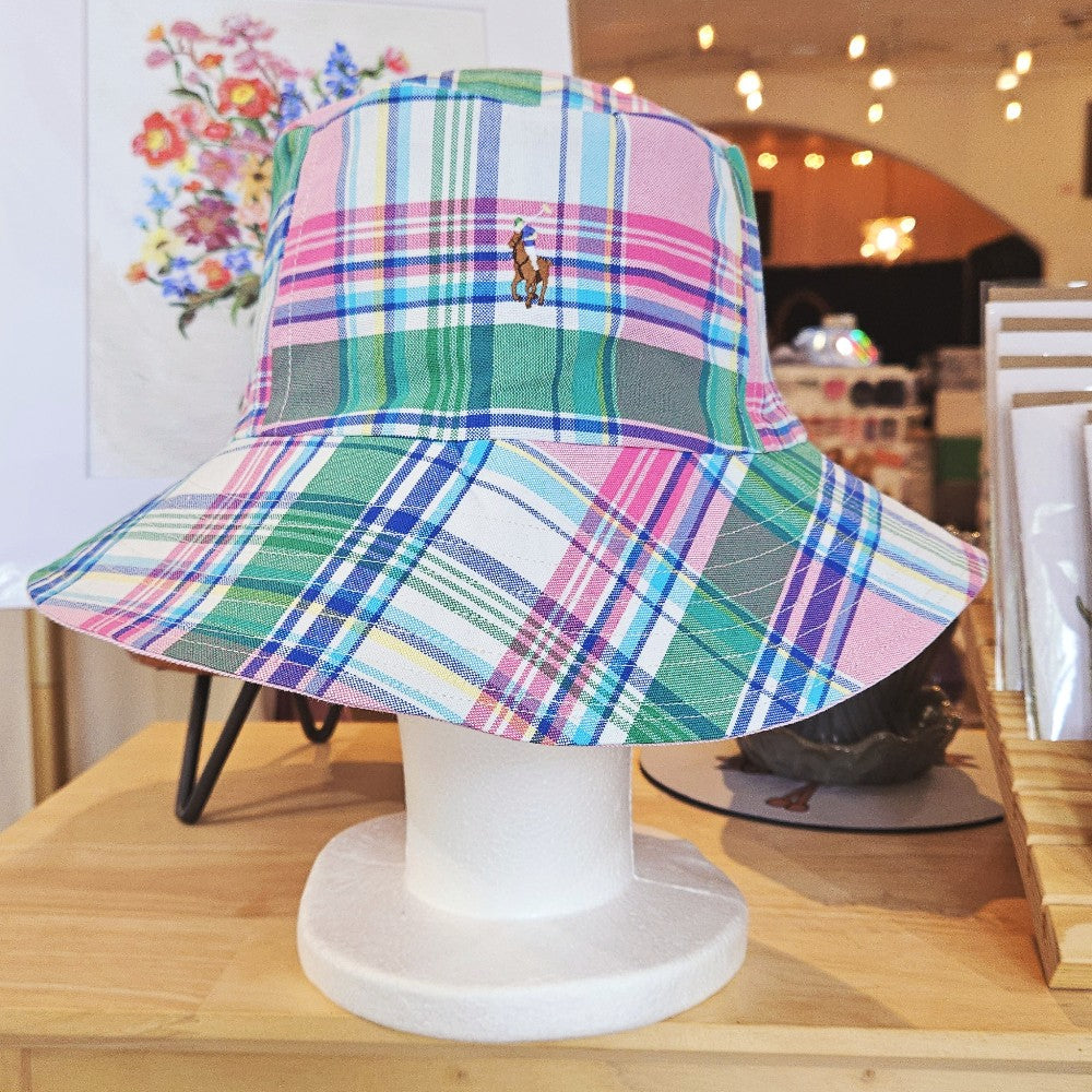 Pastel Plaid Bucket Hat Ralph Lauren that is pink, green, blue, and white modeled on a mannequin head sitting on a shelf. 