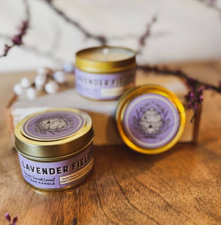Three lavender-scented candles with gold lids on a wooden surface.|415