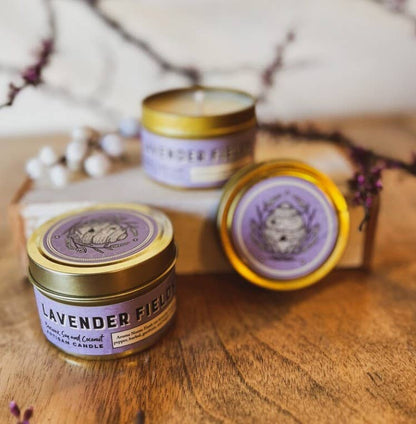 Three lavender-scented candles with gold lids on a wooden surface.|415