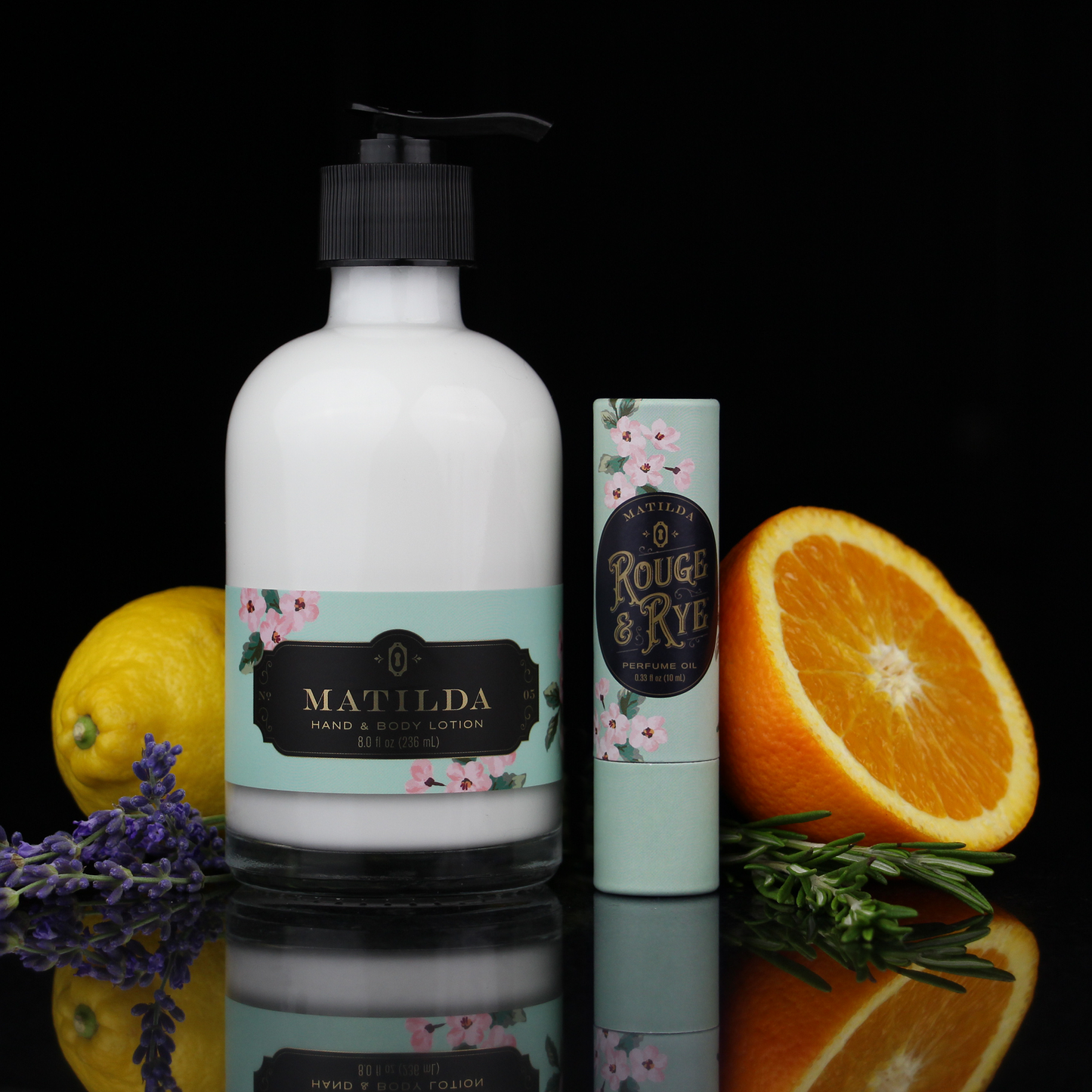 Bottle of Matilda hand and body lotion with a smaller bottle and fruits on a reflective surface.