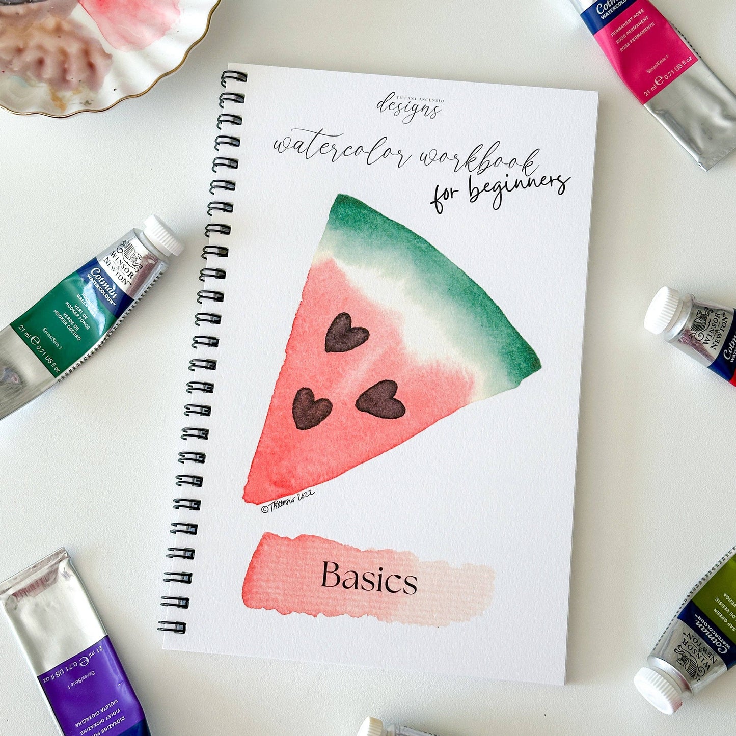 Watercolor workbook for beginners with paint tubes on a light background