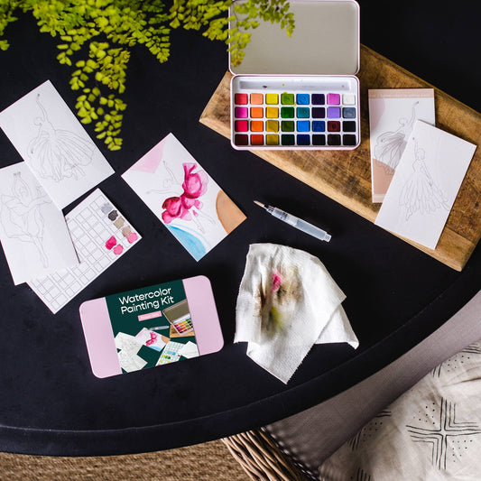 Watercolor painting kit with supplies on a black table