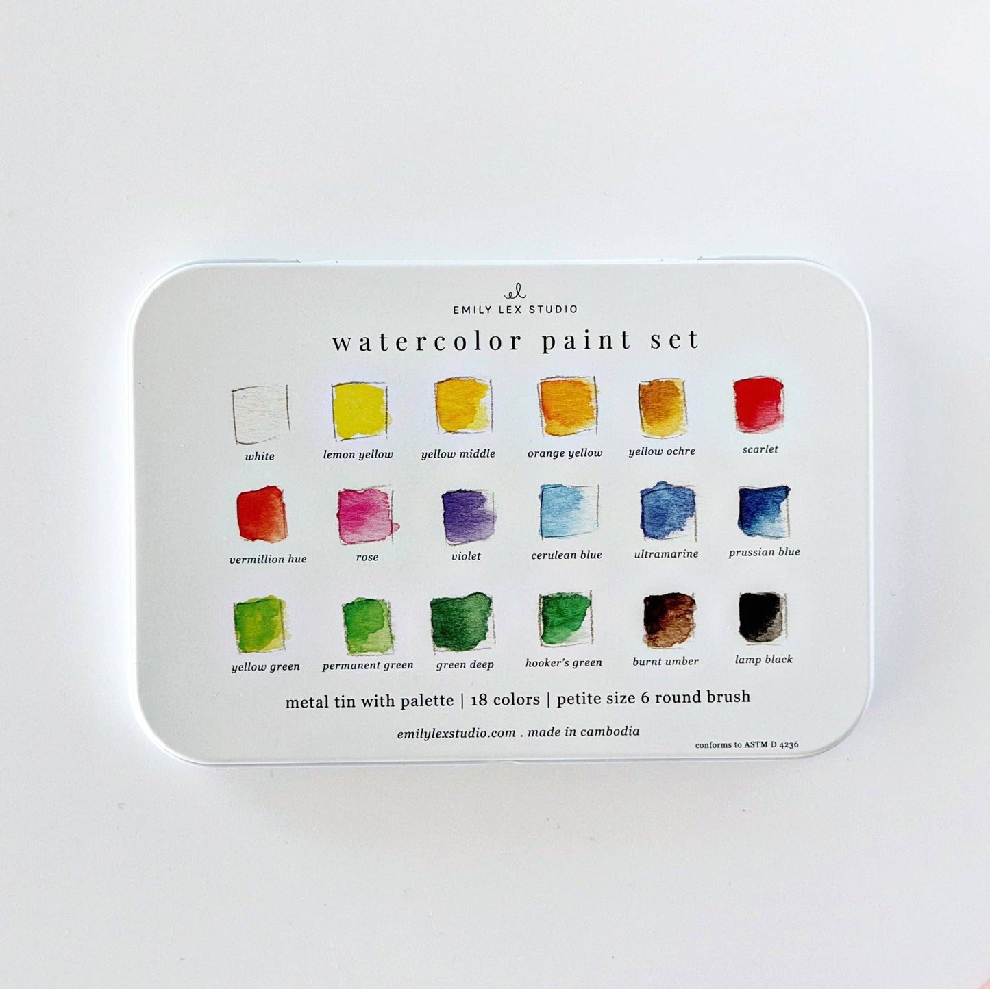 A metal tin watercolor paint set by Emily Lee Studio, showing 18 color wells with labeled watercolor swatches on a white background.