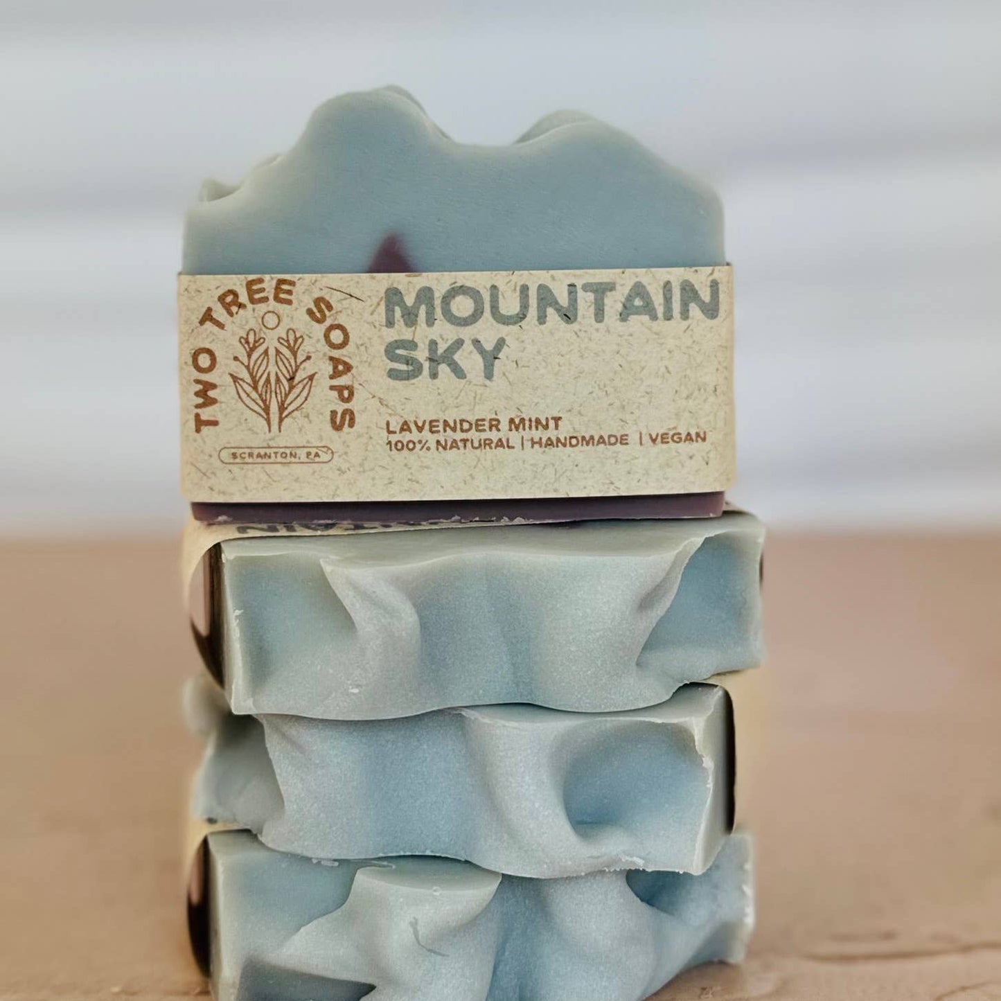 Stack of mountain sky soap bars with a visible label on a wooden surface