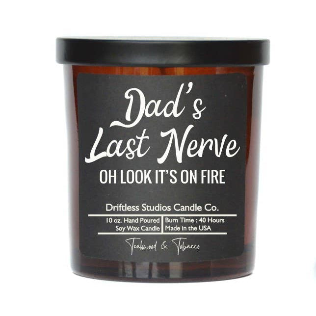 candle in amber colored glass jar with black lable and white lettering that says Dad's Last Nerve Oh look it's on fire