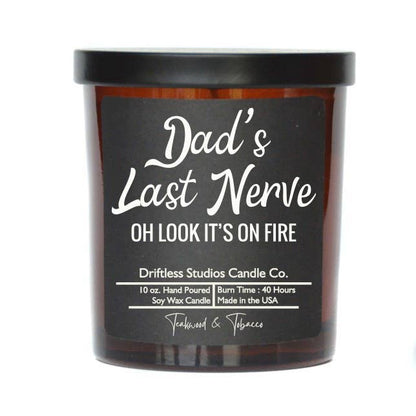 candle in amber colored glass jar with black lable and white lettering that says Dad's Last Nerve Oh look it's on fire