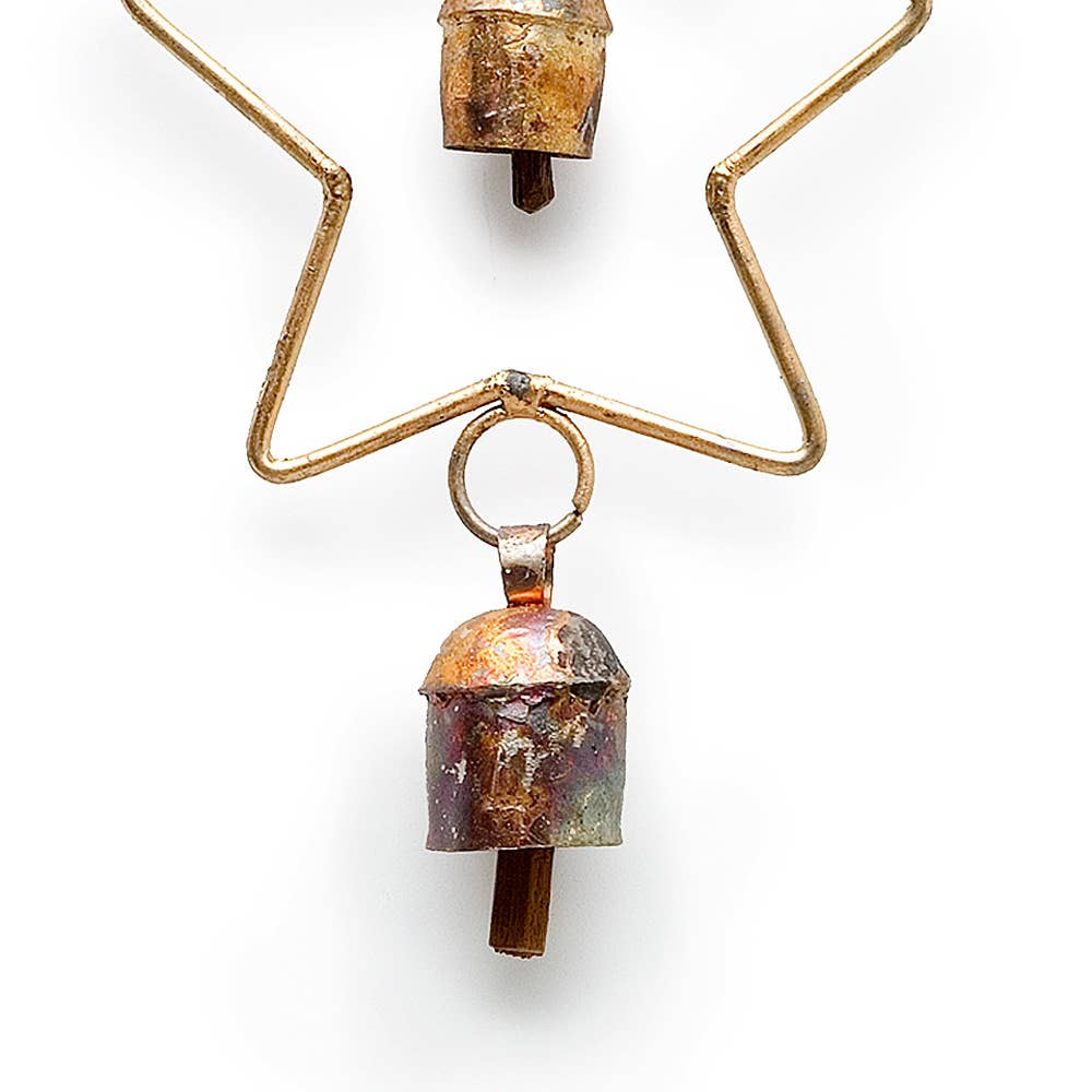 A close-up of a vintage-style metal ornament or decorative piece featuring a small bell-shaped charm with a distressed copper and iridescent finish, suspended from a gold-toned wire frame on a white background.