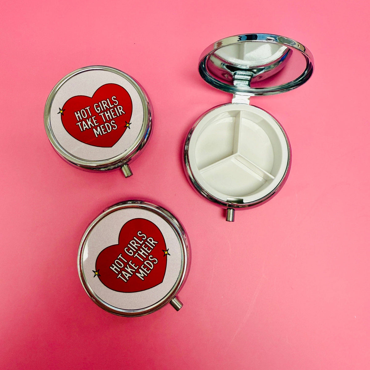 Compact mirror with 'Hot girls take their meds' text on a pink background