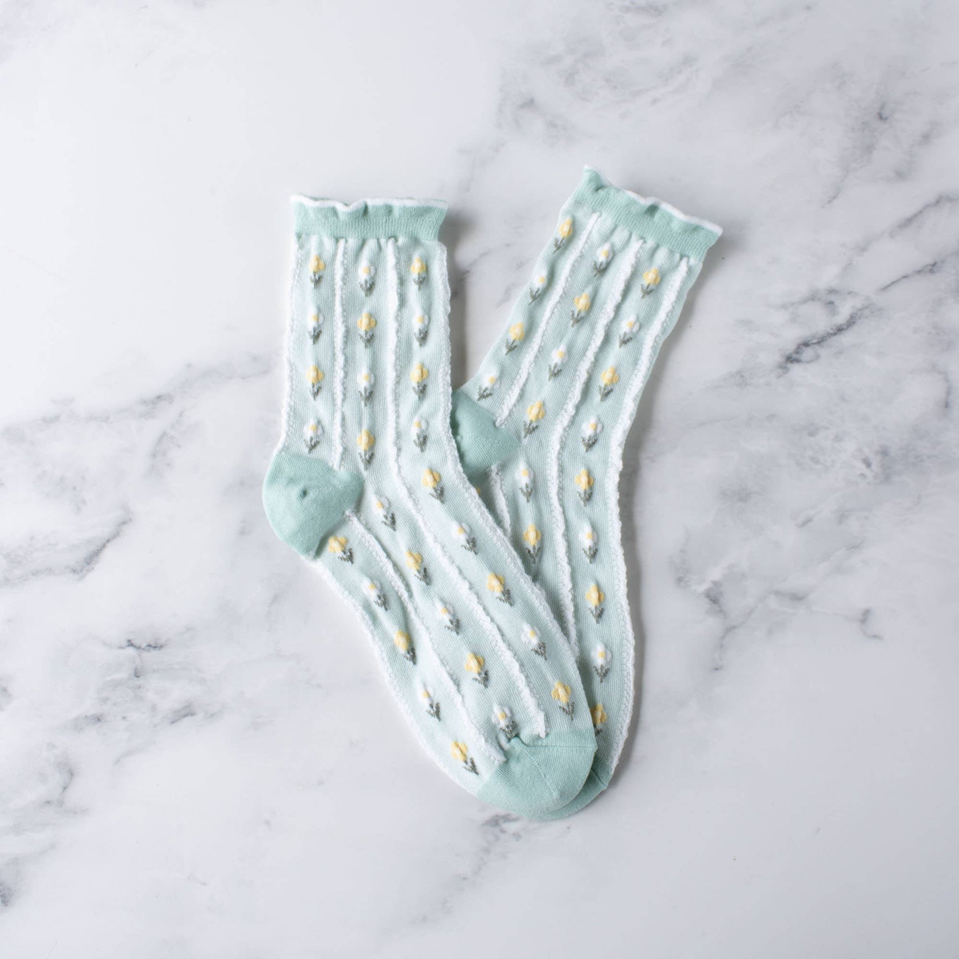 Pair of light blue socks with white polka dots on a marble surface