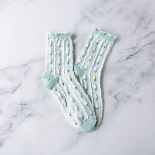 Pair of light blue socks with white polka dots on a marble surface