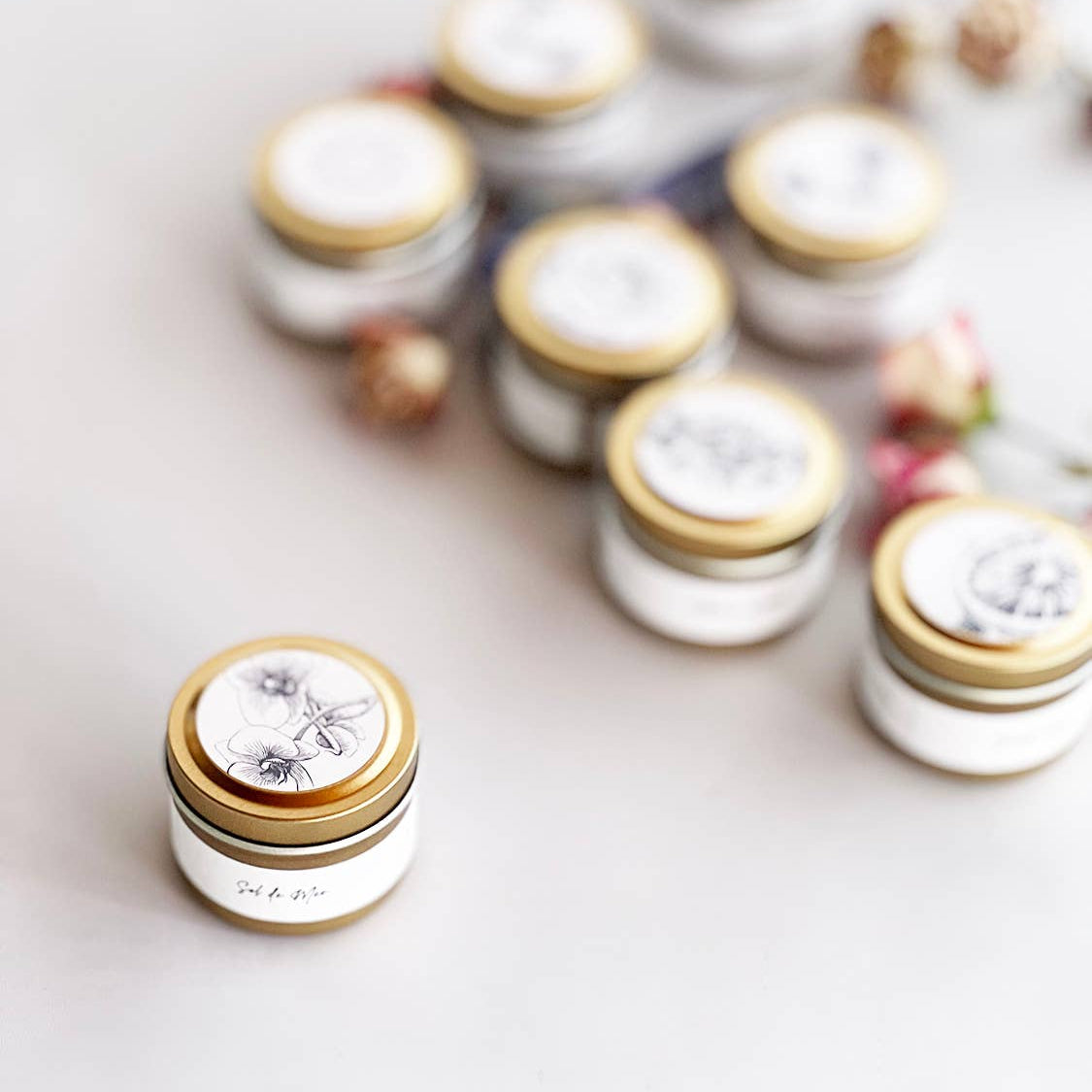 Small jars with gold lids on a light surface