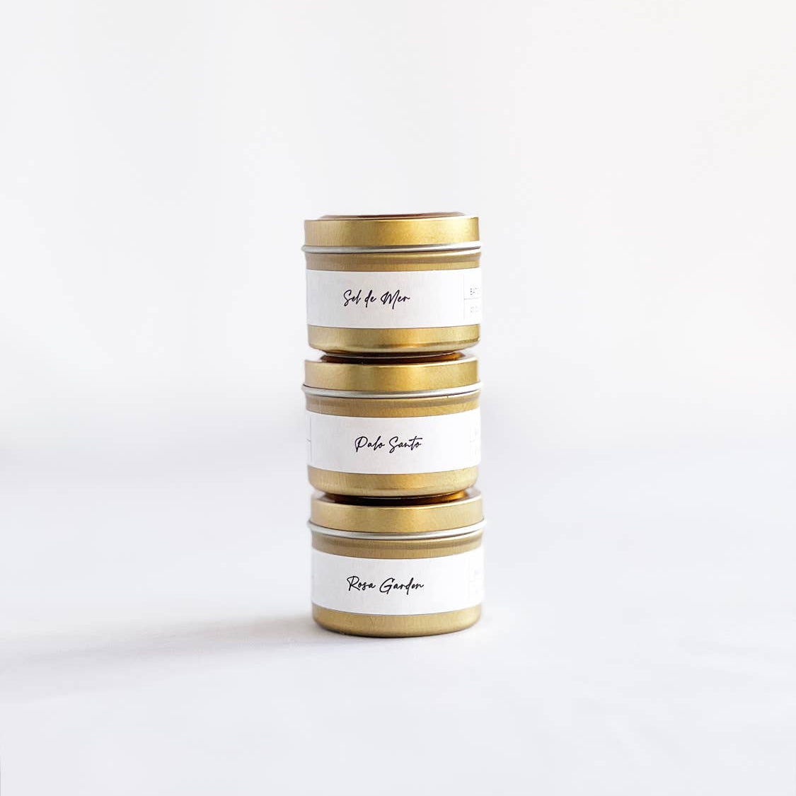 Stack of cylindrical tins with gold accents on a white background