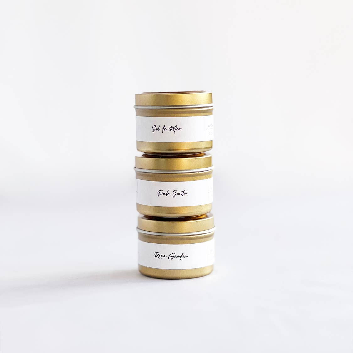 Stack of cylindrical tins with gold accents on a white background