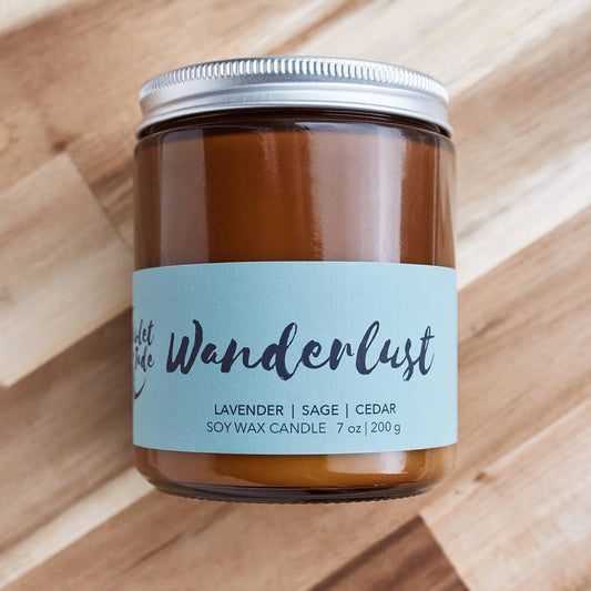 Candle jar labeled 'Wanderlust' on a wooden surface