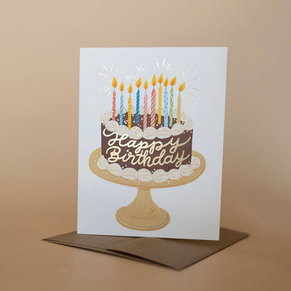 Birthday card with a cake illustration and lit candles on a brown background