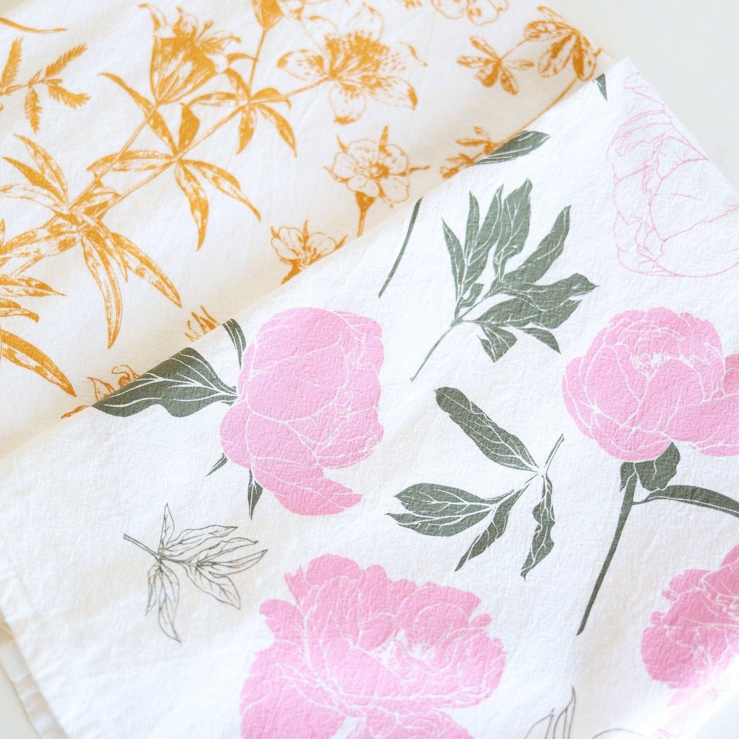 Two floral-patterned cloths with pink flowers and green leaves on a white background.