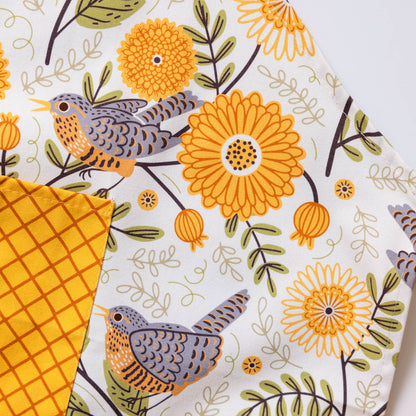 Fabric swatches with a floral and bird pattern on one and a solid yellow checkered pattern on another, against a white background.