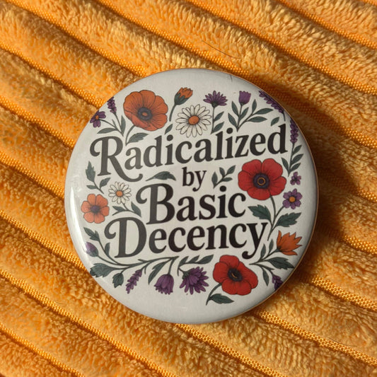Button badge with floral design and text 'Radicalized by Basic Decency' on a textured orange background