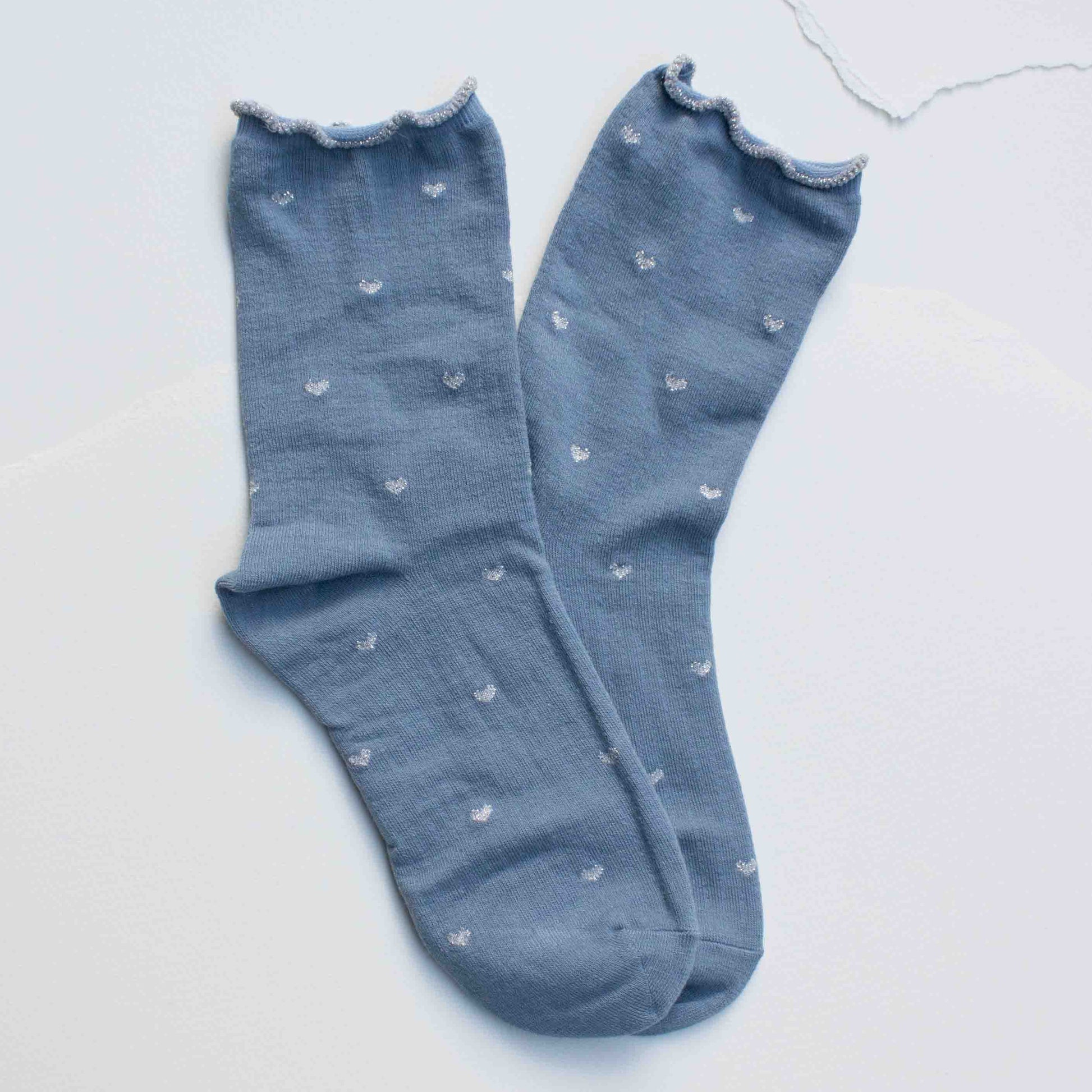 Pair of blue socks with small white patterns on a light gray background
