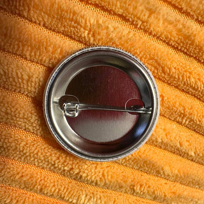 Round metal button on a textured orange fabric background